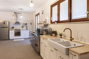 A modern kitchen with stainless steel appliances, a double sink, and wooden cabinets. - Beautiful villa with pool in the hills of Le Marche,20 minutes from the beaches of Porto San Giorgio (Ponzano di Fermo)