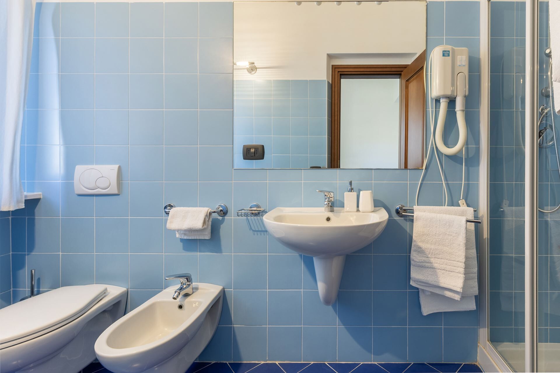 A bathroom with a bidet, a sink, and a mirror.
