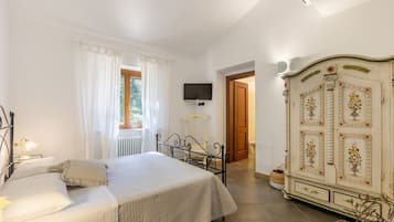 Una camera da letto con un letto, una TV a parete, un termosifone e un armadio decorato con motivi floreali.
