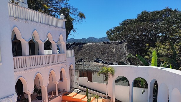 A pool area with a clear blue pool, white walls, and arches. - Ocean view apartment with pool in San Pancho - Casa Blanca (San Francisco)