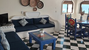 A living room with a checkered floor, a sofa, a coffee table, and a ceiling fan. - Ocean view apartment with pool in San Pancho - Casa Blanca (San Francisco)