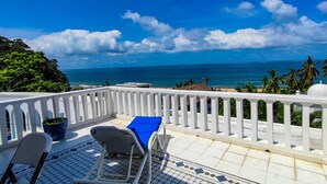 A balcony with a white railing, a blue lounge chair, and a potted plant. - Ocean view apartment with pool in San Pancho - Casa Blanca (San Francisco)
