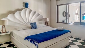 A hotel room with a large bed, a ceiling fan, a window with a view, and a checkered floor. - Ocean view apartment with pool in San Pancho - Casa Blanca (San Francisco)