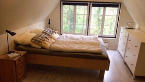 A bedroom with a single bed, a nightstand, a dresser, and a window with a view of trees. - 4 Star Holiday Home in Sydals (Sydals)
