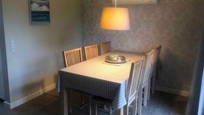 A dining area with a table and chairs, an air conditioning unit on the wall, and a painting of clouds. - 4 Star Holiday Home in Sydals (Sydals)