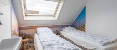 A bedroom with two beds, a skylight, a bathtub, and a small stool.