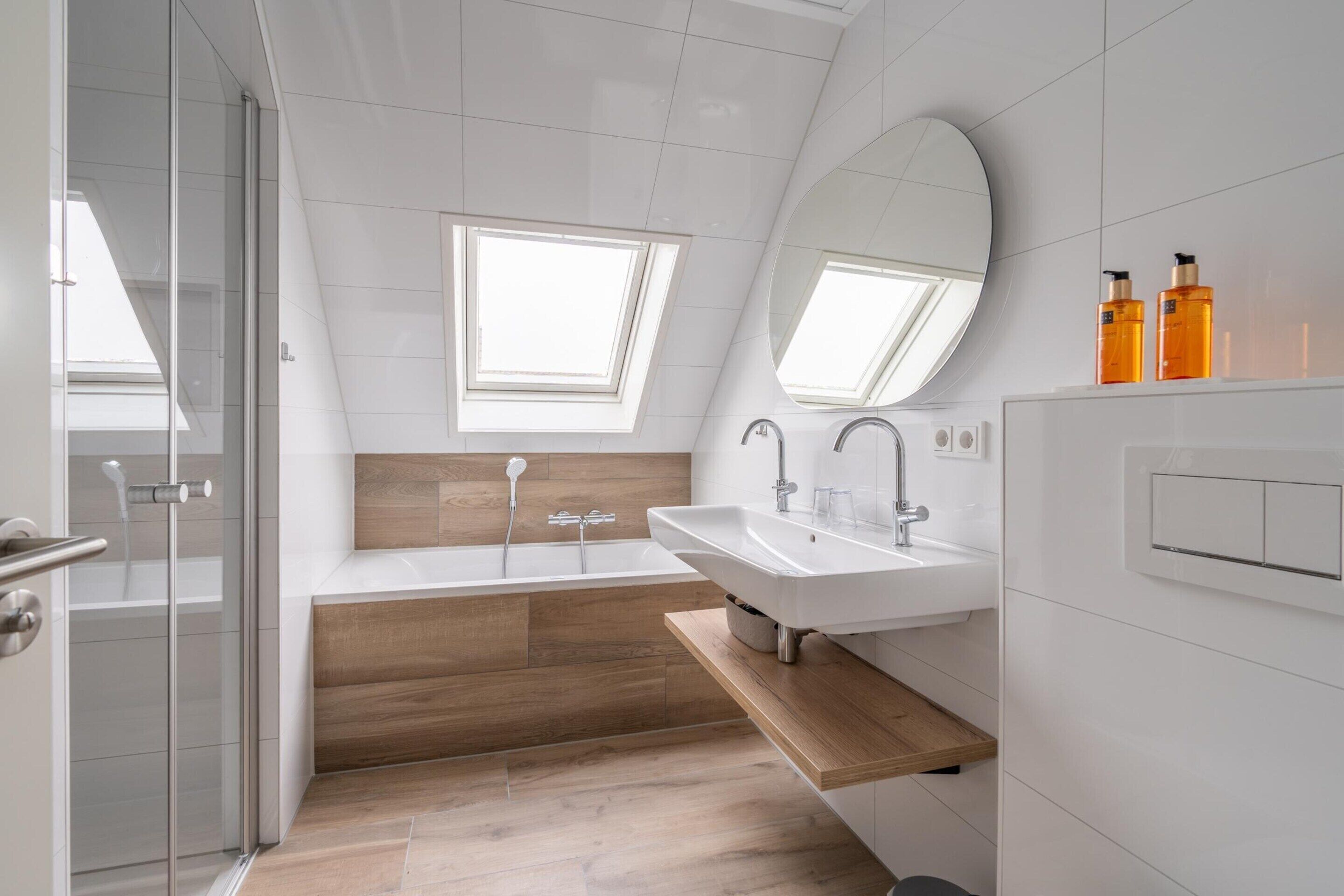 Ein modernes Badezimmer mit Duschkabine aus Glas, einer freistehenden Badewanne und einem Waschtisch mit Spiegel.