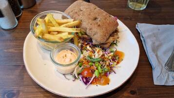 A plate with a sandwich, fries, and a salad with dressing.