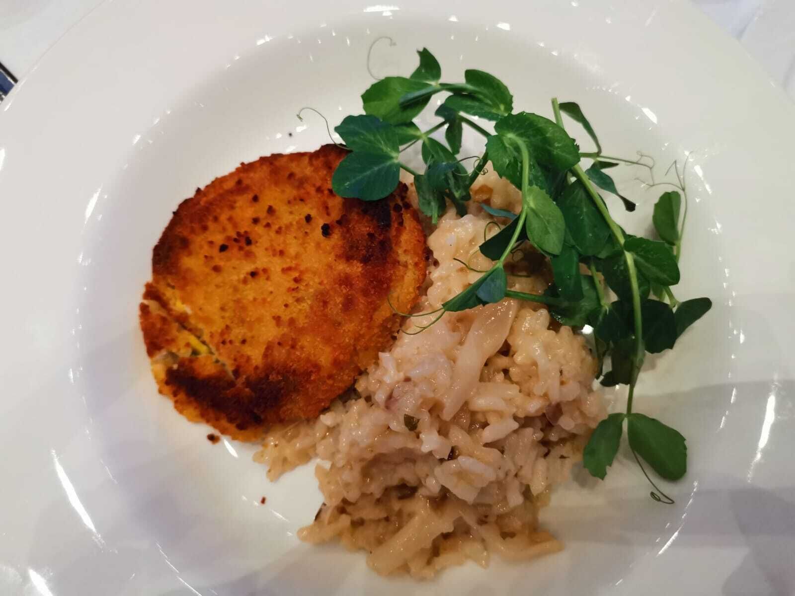 Une assiette comprenant un plat frit, un plat à base de céréales et des légumes verts.