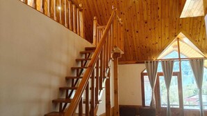 Una escalera de madera conduce a un nivel superior con vistas al exterior a través de amplios ventanales.
