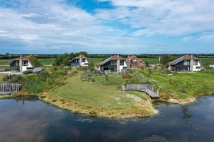 Uma área residencial com casas modernas, um lago e um campo gramado.