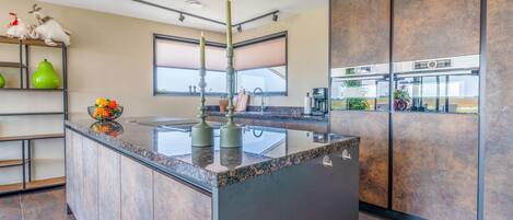 A modern kitchen with a central island, built-in appliances, and a large window.