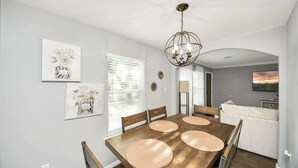 Een eetruimte met een houten tafel, vier stoelen en een kroonluchter.
