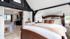 Ein geräumiges Schlafzimmer mit einem großen Bett, Holzbalken und Blick ins Freie.