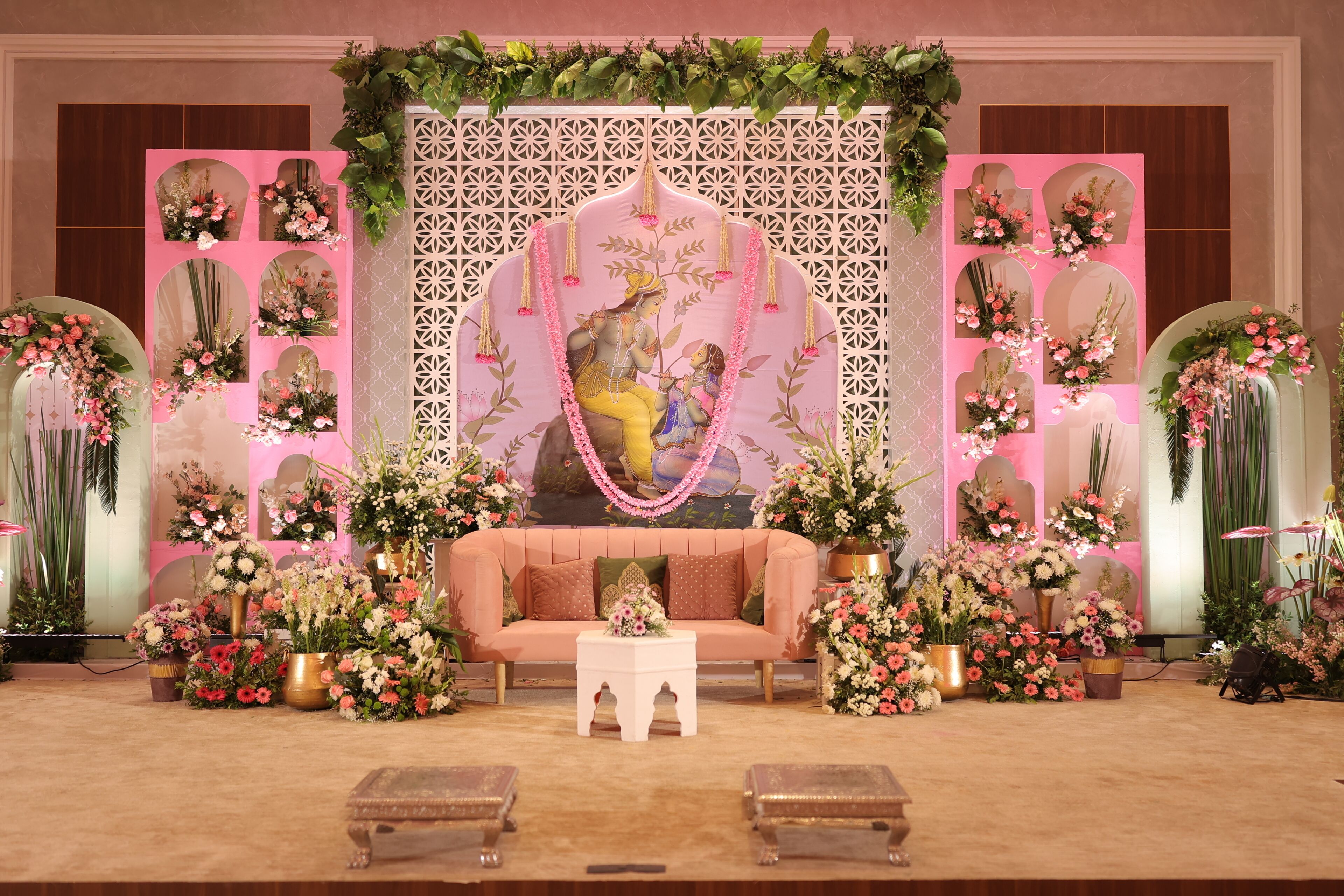 A stage with a sofa, a small table, and decorative floral arrangements.