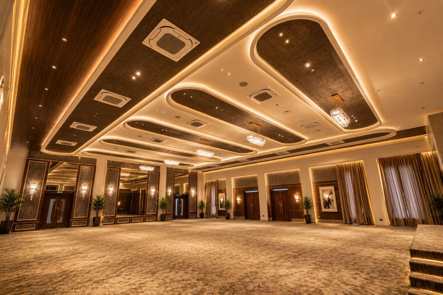 Un vestíbul d'hotel ampli, amb un sostre alt, il·luminació empotrada i un sòl amb moqueta.