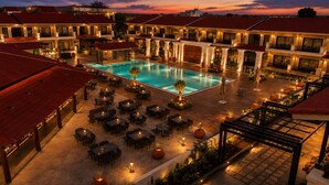 A hotel with a swimming pool, outdoor seating, and multiple buildings with red roofs. - Mangalam Resort and Spa - Member of Absolute Collection   (Gangapur)