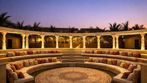 A circular outdoor seating area with sofas and a central rug, surrounded by a covered structure with pillars. - Mangalam Resort and Spa - Member of Absolute Collection   (Gangapur)
