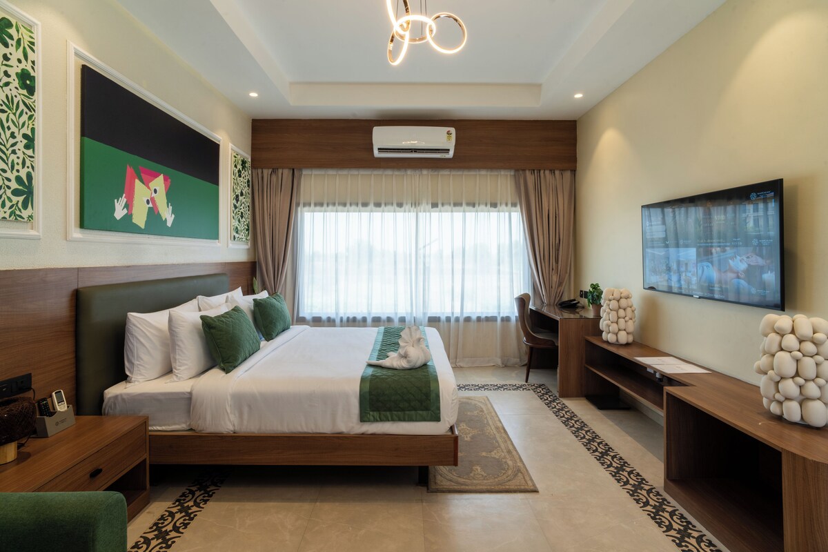 A modern hotel room with a bed, a TV, an air conditioning unit, a desk, and a chair.