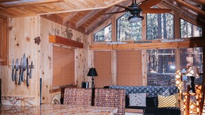 Ein Holzblockhaus Innenansicht mit Küchenzeile, Esstisch und Bett.