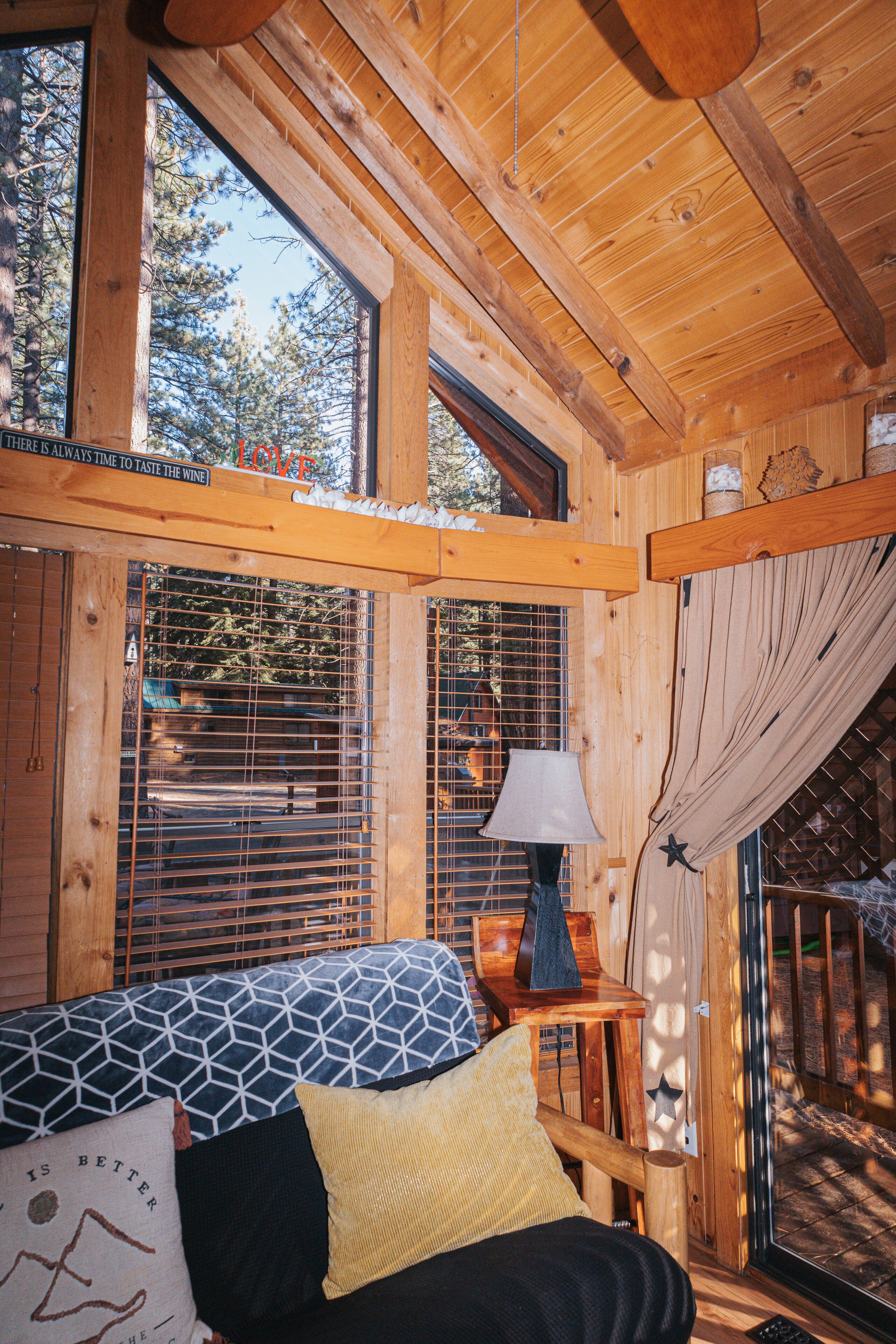 A wooden cabin room with a bed, a window, and a lamp.