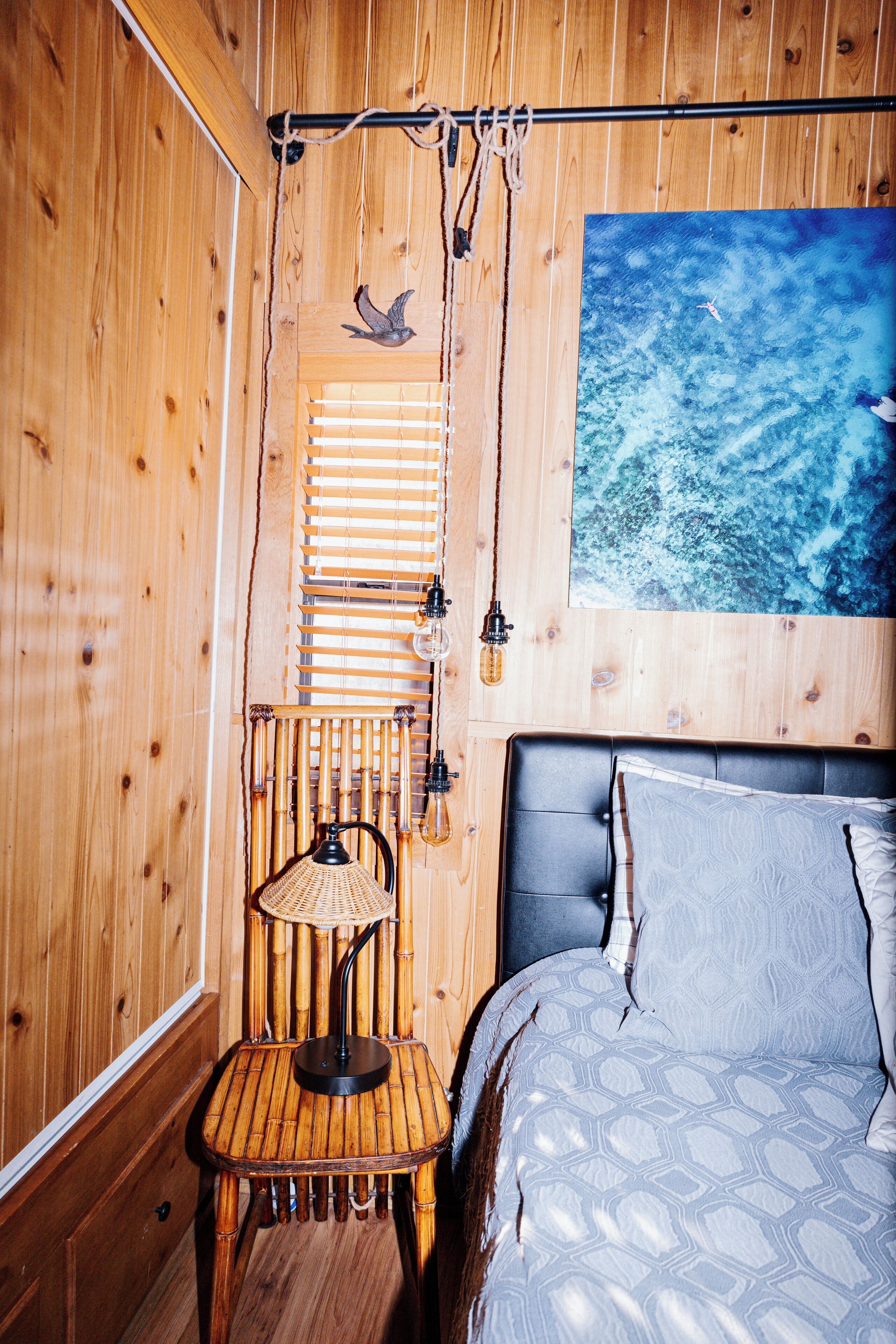 Ein Zimmer mit Holzboden, einem Bett, einem Sessel und einer Wandleuchte.