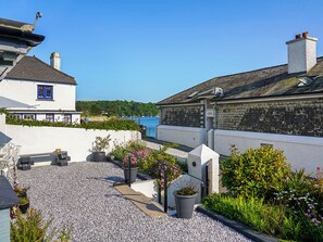 A coastal building with a gravel patio, potted plants, and a view of the sea. - 3 bedroom accommodation in St Mawes (St Mawes)