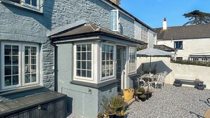 Kaksikerroksinen talo, jossa on kiviverhous, katettu terassi ulkokalusteineen ja pieni puutarha-alue.