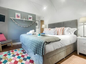 Una camera da letto con un letto, comodini, una sedia, un tappeto colorato e decorazioni alle pareti.