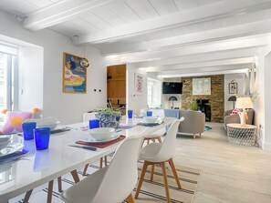 Un'area pranzo moderna con un tavolo bianco, bicchieri di vetro blu e un vaso decorativo.