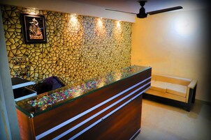 Ein Empfangsbereich mit einer Wand aus Mosaiken, einem hölzernen Empfangstresen und einem beigefarbenen Sofa.