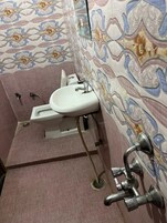 Ein Badezimmer mit Toilette, Waschbecken und zwei Wasserhähnen.