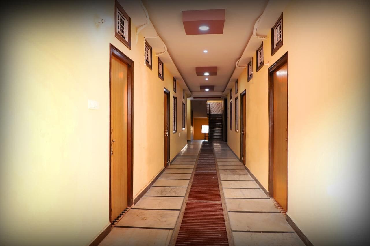 A long, narrow hallway with wooden doors on both sides, leading to a staircase at the end.