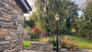 Ein Steinhaus mit einem Ziegelweg, der zu einem Garten mit einer Lampe führt.