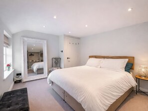 A bedroom with a large bed, a wardrobe, a mirror, and a small table with a lamp. - Mill House - UK50646 (Falmouth)