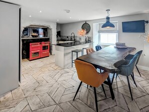 A modern kitchen with red appliances, a central island, and a dining area with chairs and a table.