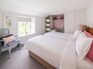 A bedroom with a large bed, a chair, a window, and built-in shelves.