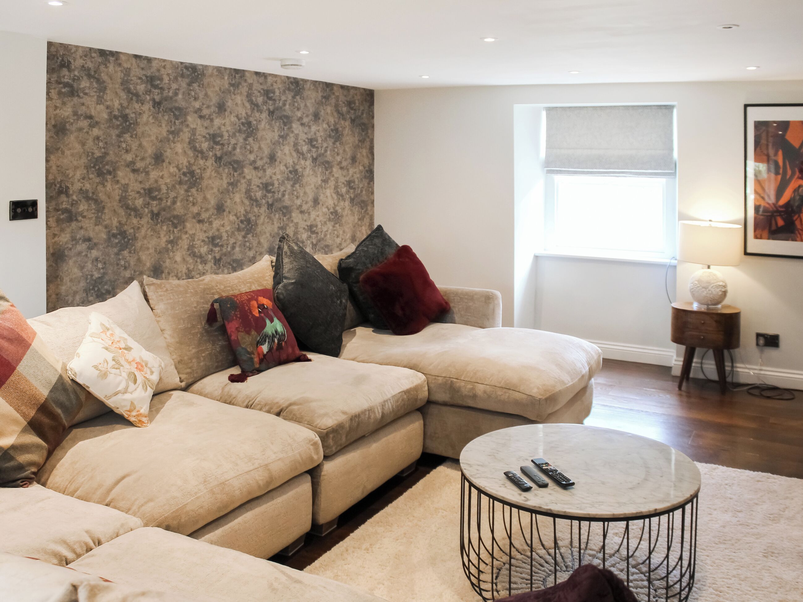 A modern living room with a sectional sofa, a round coffee table, and a large window with a view.