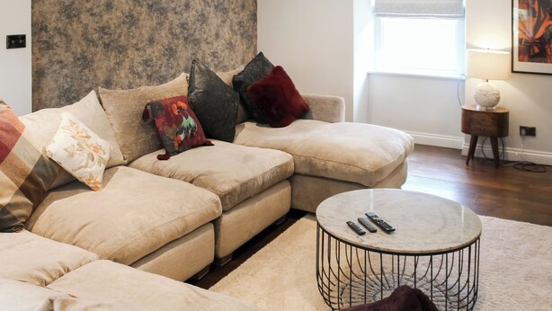 A modern living room with a sectional sofa, a round coffee table, and a large window with a view. - Mill House - UK50646 (Falmouth)