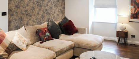 A modern living room with a sectional sofa, a round coffee table, and a large window with a view.