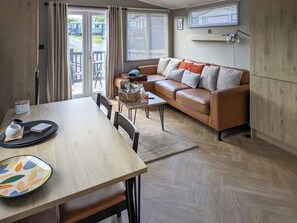 Ein modernes Wohnzimmer mit einer Couch, einem Esstisch, Stühlen und einem an der Wand befestigten Fernseher.