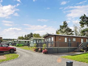 A caravan park with multiple caravans, a red car parked in front, and a wooden building labeled 'Wanderhome.'