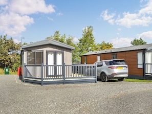 A caravan park with a small wooden building, a fenced area, and a white Discovery SUV parked.
