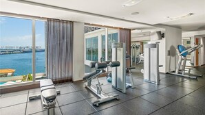 Une salle de sport moderne équipée de matériel d’exercice, dotée de grandes fenêtres et offrant une vue sur l’eau.