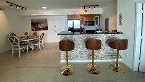 Une cuisine moderne dotée d’un îlot central, de tabourets de bar et d’un coin repas avec une table et des chaises.