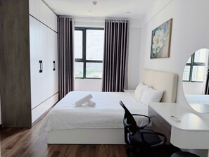 Una camera d'albergo con un letto, una scrivania, una sedia, un quadro e una finestra con tende.