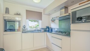 Een moderne keuken met witte kasten, een ingebouwde oven, een gasfornuis en een Siemens klok.
