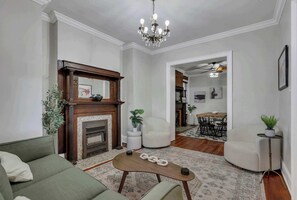Una sala de estar con chimenea, un sofá, una mesa de centro y un área de comedor al fondo.