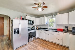 A kitchen with white cabinets, stainless steel appliances, a water dispenser, and a ceiling fan. - Walk to Restaurant & Bar: Home w/ Deck in Gary (Gary)