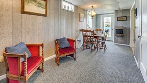 A room with wooden panel walls, a red cushioned bench, a wooden dining table with chairs, and a ceiling fan.